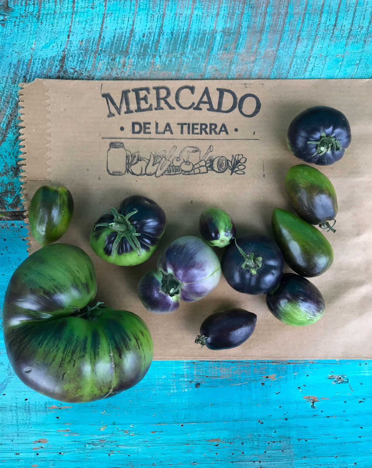 Tomates negros y verdes cosechados sobre una bolsa de papel de Mercado de la Tierra